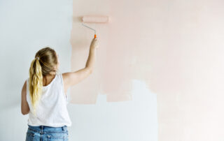 Woman painting a wall with roller brush